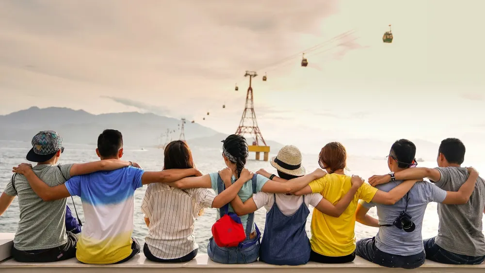 Un groupe assis côte à côte, face à la mer et aux montagnes